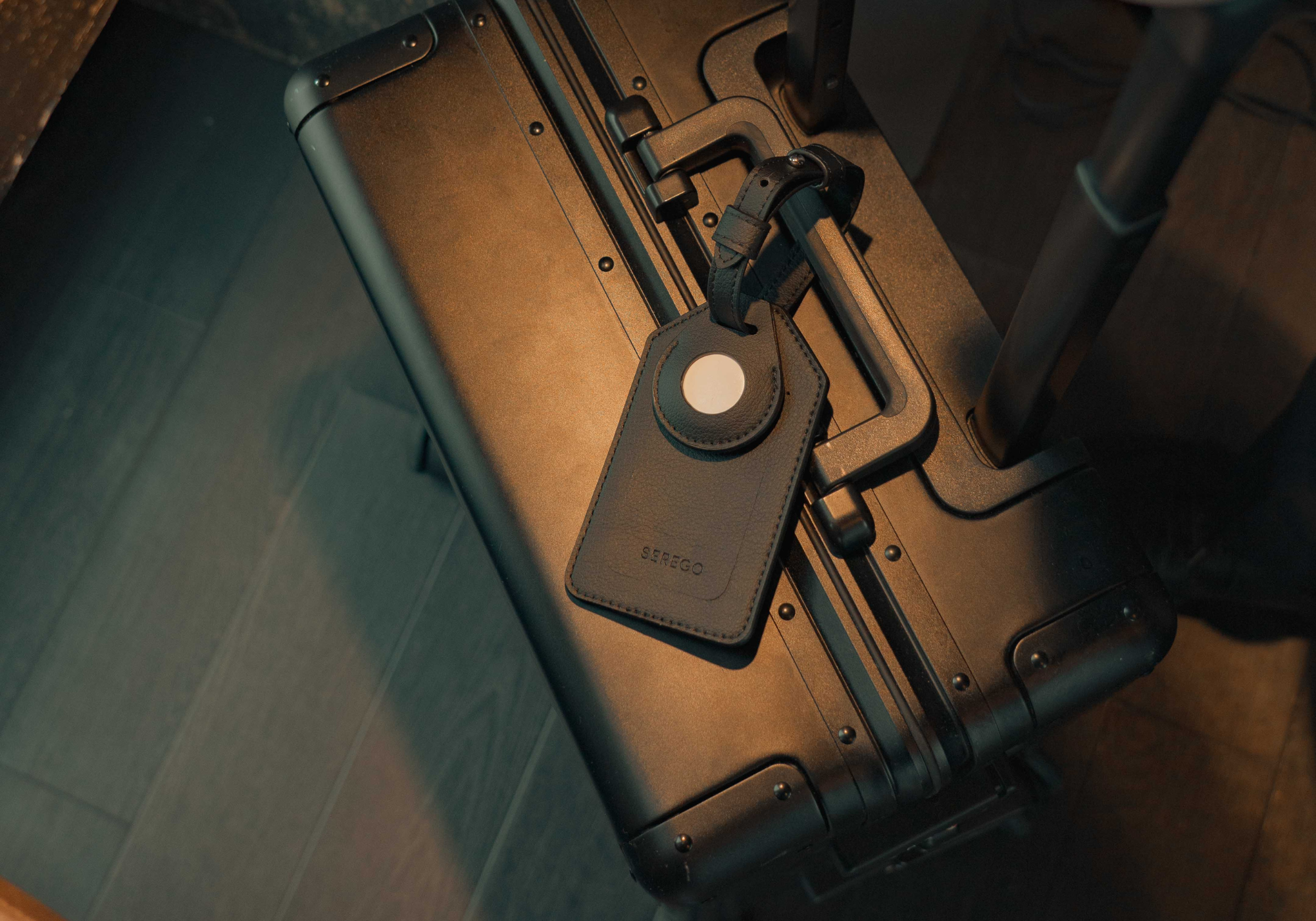 SEREGO black vegan leather luggage tag attached to suitcase, AirTag ready travel label